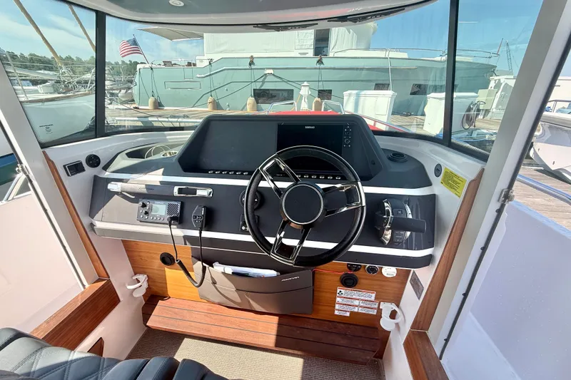 Slide: The Image of 2022 Axopar 28 Cabin boat helm with modern steering and navigation controls. - 19