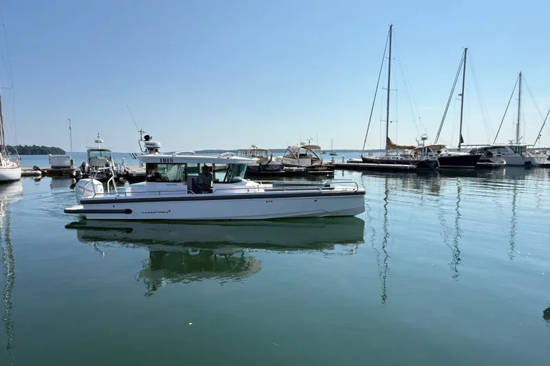 Slide: The Image of 2022 Axopar 28 Cabin boat docked in a marina with sailboats in the background. - 39