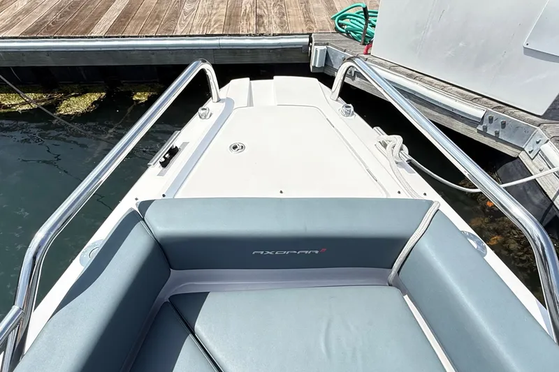 Slide: The Image of 2022 Axopar 28 Cabin boat docked, featuring sleek seating and stainless steel railings. - 29