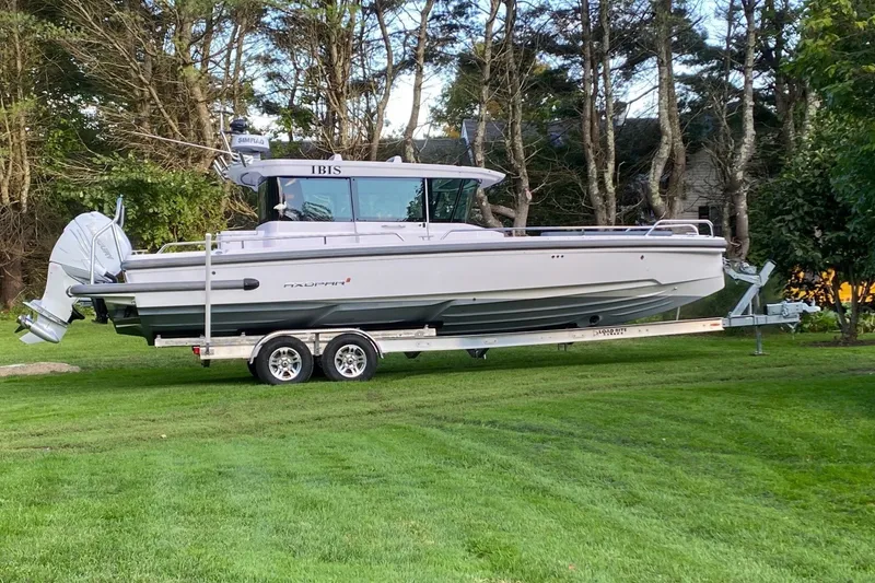 Slide: The Image of A 2022 Axopar 28 Cabin boat on a trailer, set on a grassy lawn. - 42
