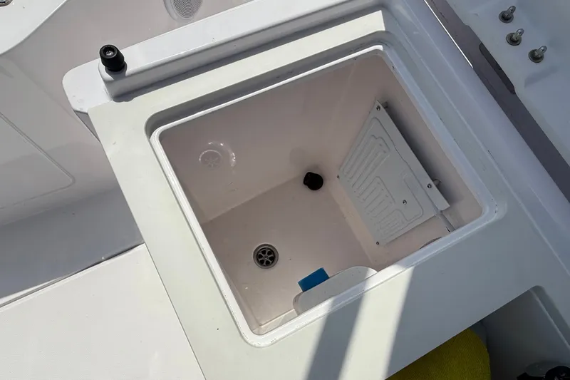 Slide: The Image of Storage compartment on a 2022 Axopar 28 Cabin boat, featuring a drain and lid. - 15