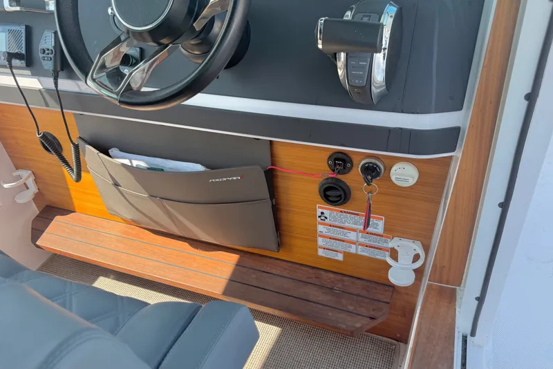 Slide: The Image of 2022 Axopar 28 Cabin helm with steering wheel, controls, and storage pocket. - 20