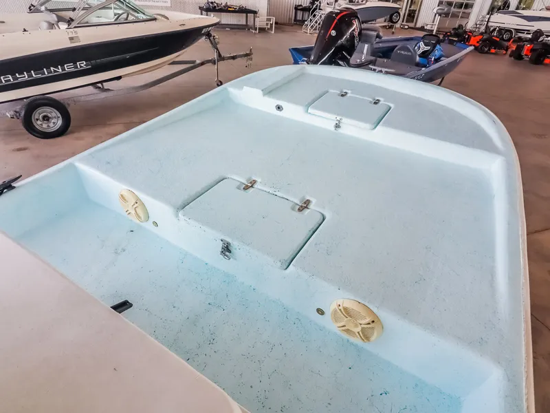 Slide: The Image of An open boat with a blue surface and two speakers. It's indoors next to other boats. - 16