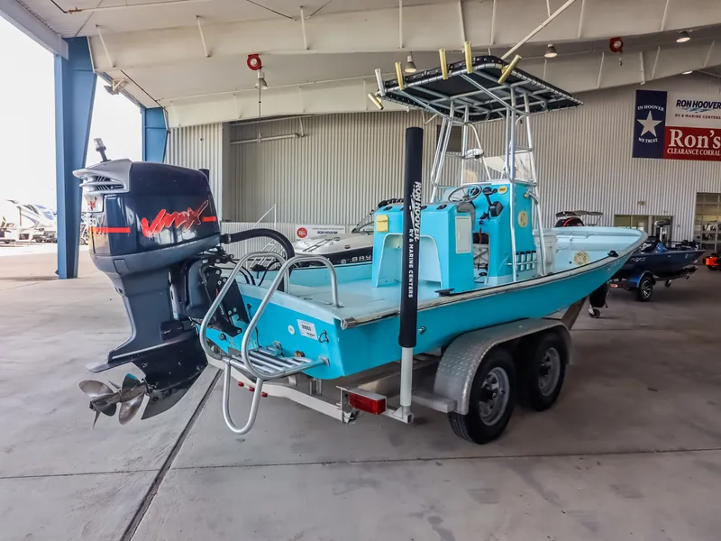 Slide: The Image of A turquoise boat with an outboard motor sits on a trailer in a warehouse. - 8