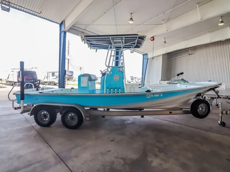 Slide: The Image of A blue boat with a T-top on a trailer in a covered storage area. - 10