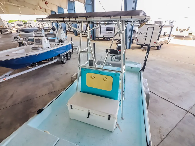 Slide: The Image of A boat with a blue deck and white seat under a covered area. Other boats are visible in the background. - 13