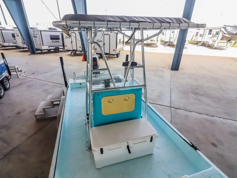 Slide: The Image of A small boat with a blue deck and white seat. It has a sunshade and is parked indoors. - 14