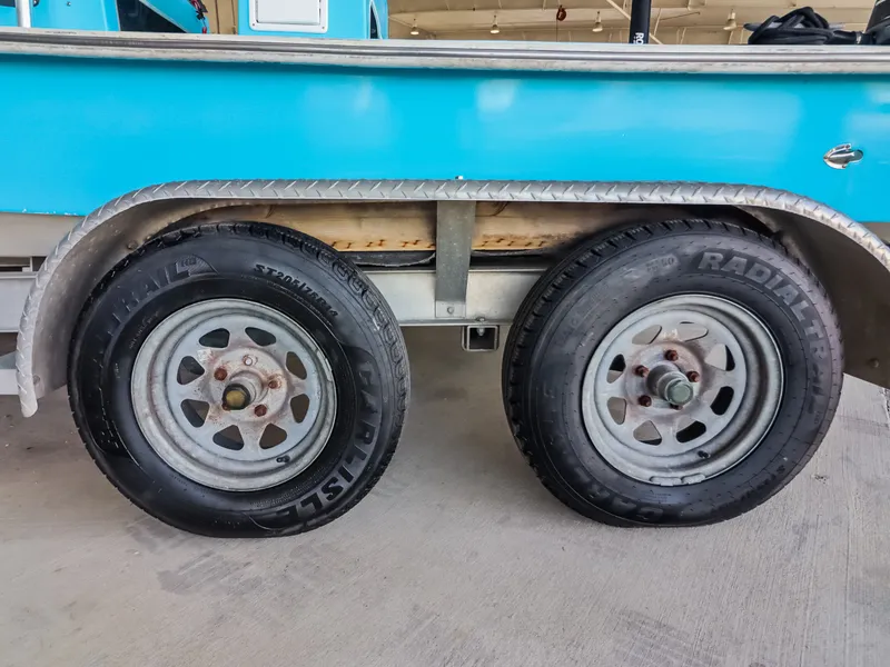 Slide: The Image of Close-up of two trailer wheels under a blue boat on a trailer. - 23