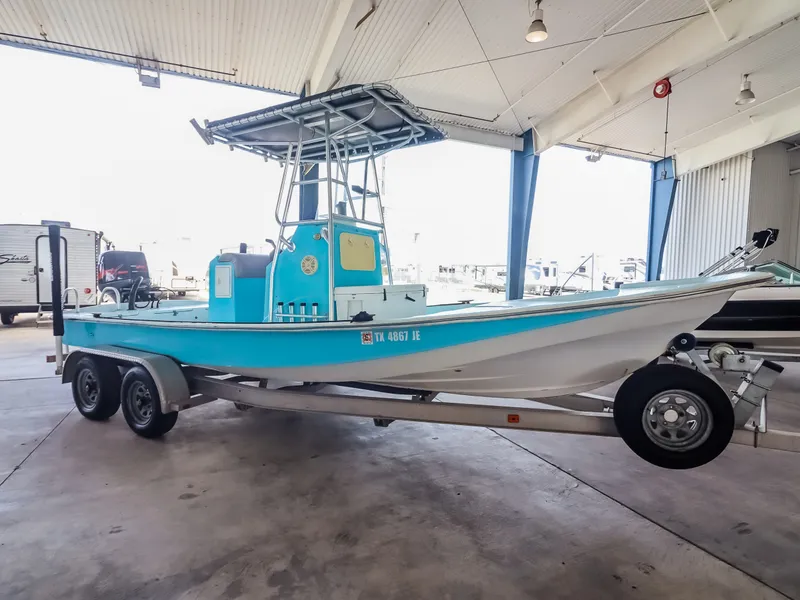 Slide: The Image of A blue and white boat with T-tops sits on a trailer in a covered storage area. - 11