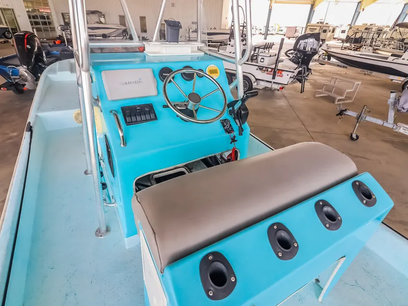 Slide: The Image of A blue boat with a helm, steering wheel, and bench seat. It's in a warehouse. - 17