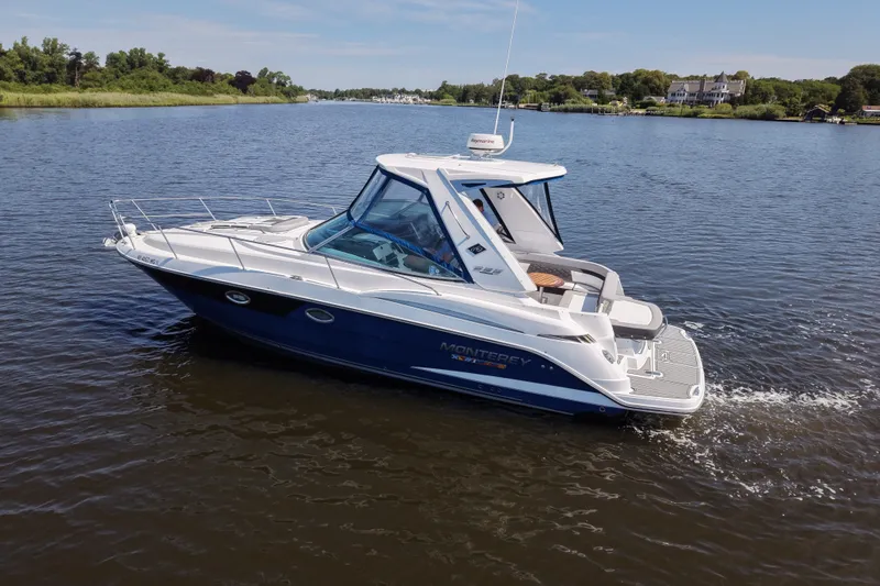 Slide: The Image of 2021 Monterey 335 Sport Yacht cruising on a serene lake with lush greenery. - 5