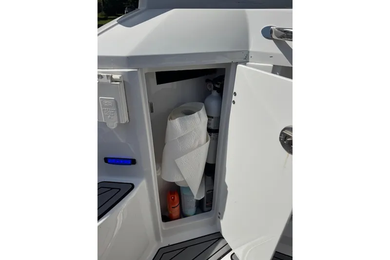 Slide: The Image of Open storage compartment on 2021 Monterey 335 Sport Yacht with paper towels and cleaning supplies. - 54