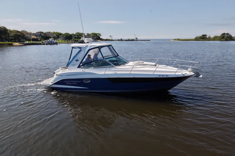 Slide: The Image of 2021 Monterey 335 Sport Yacht cruising on a calm river under a clear sky. - 2
