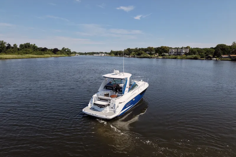 Slide: The Image of 2021 Monterey 335 Sport Yacht cruising on a serene river under a clear blue sky. - 16