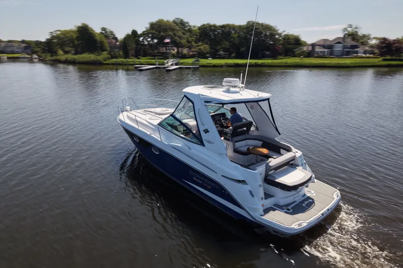 Slide: The Image of 2021 Monterey 335 Sport Yacht cruising on a serene lake with lush greenery. - 18