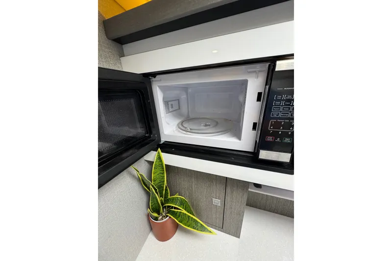 Slide: The Image of Open microwave in 2021 Monterey 335 Sport Yacht interior, with a potted plant nearby. - 28