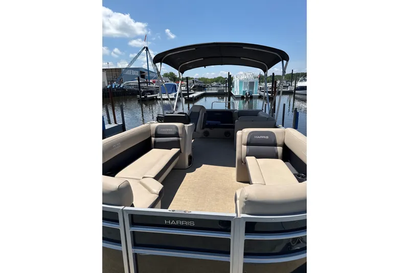 Slide: The Image of 2024 Harris Cruiser 230 pontoon boat with spacious seating at a marina. - 2