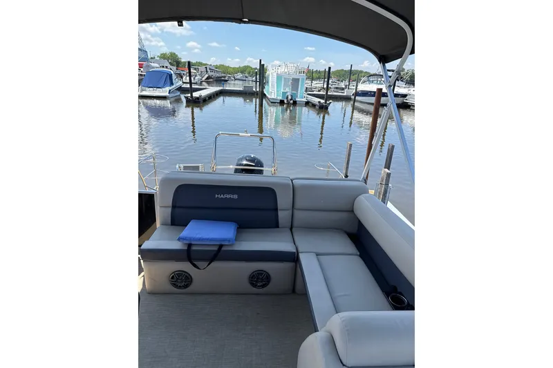 Slide: The Image of 2024 Harris Cruiser 230 pontoon boat interior at marina, featuring comfortable seating. - 6