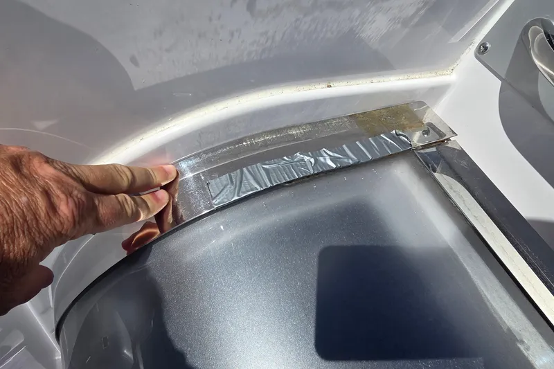 Slide: The Image of Hand inspecting duct tape repair on 2006 Donzi 38 ZR boat surface. - 16