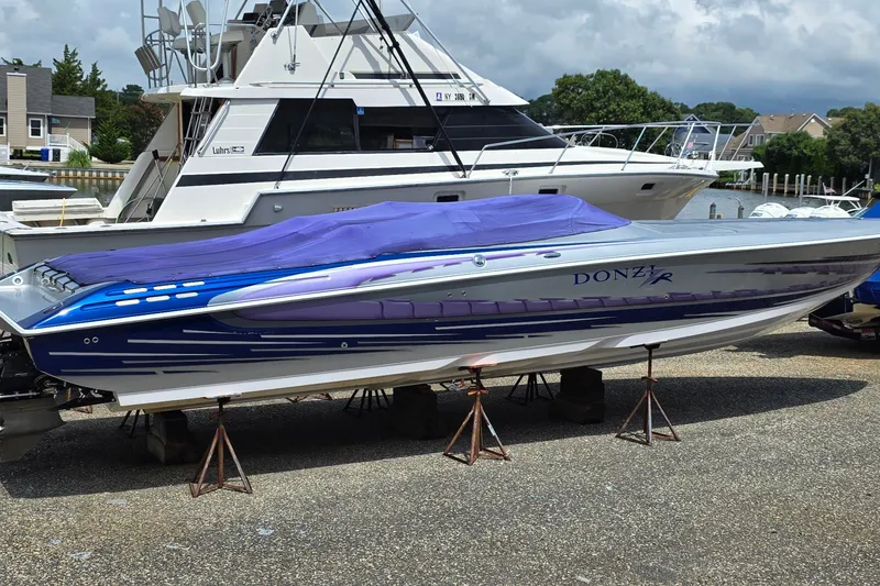 The Image of 2006 Donzi 38 ZR speedboat with blue and purple cover, docked at marina. - 0