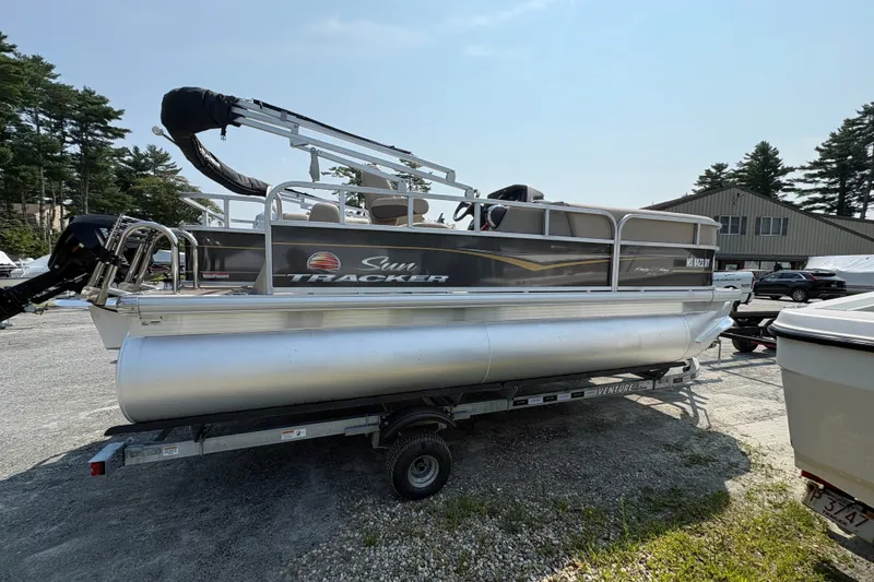 The Image of 2025 Sun Tracker Party Barge 18 DLX pontoon boat on trailer, parked outdoors. - 0
