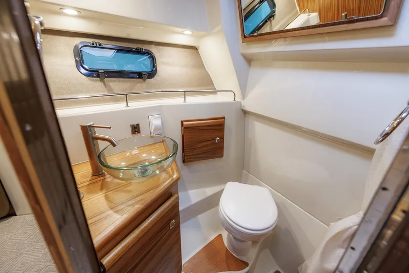 Slide: The Image of 2026 Ranger Tugs R-27 boat bathroom with modern glass sink and wooden accents. - 27