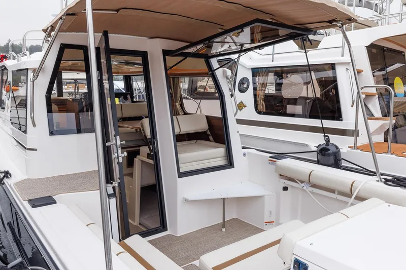 Slide: The Image of 2026 Ranger Tugs R-27 boat interior with seating and open cabin door. - 17