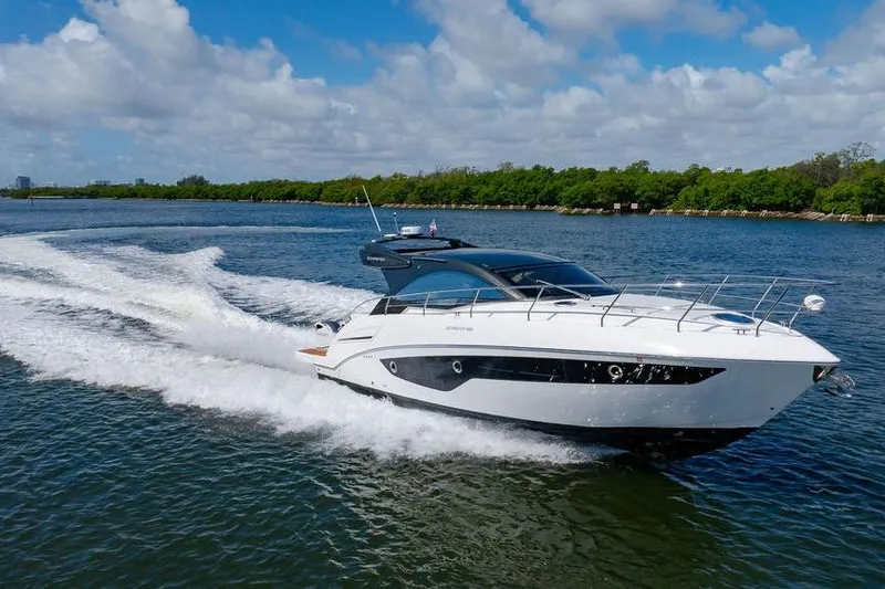 Slide: The Image of 2022 Schaefer 400 Sport yacht cruising on a sunny day, surrounded by lush greenery. - 8