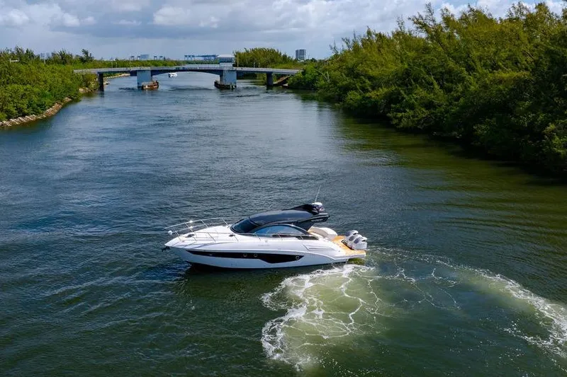 Slide: The Image of 2022 Schaefer 400 Sport yacht cruising on a scenic river under a cloudy sky. - 10