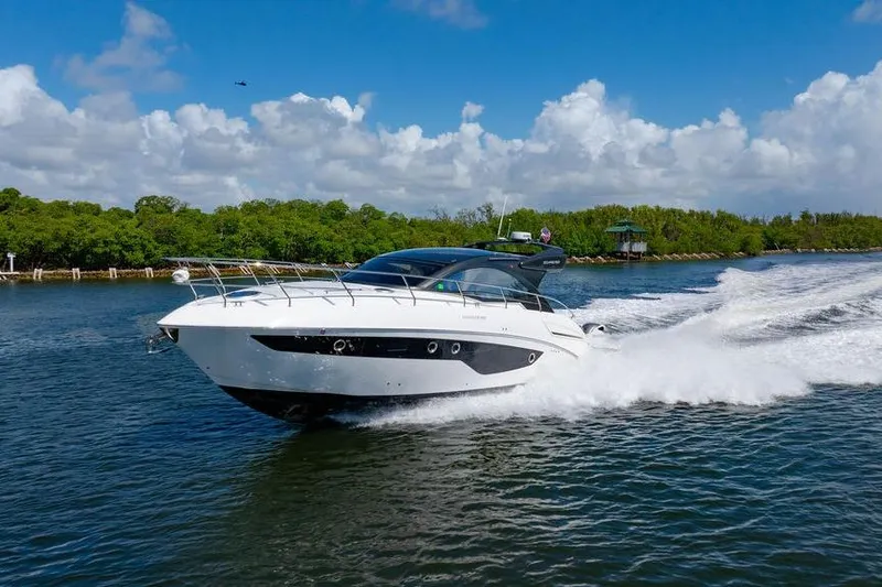 Slide: The Image of 2022 Schaefer 400 Sport yacht cruising on a sunny day, surrounded by lush greenery. - 6