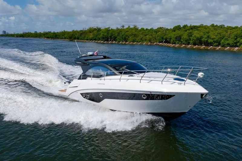 Slide: The Image of 2022 Schaefer 400 Sport yacht cruising on a scenic waterway with lush greenery. - 19