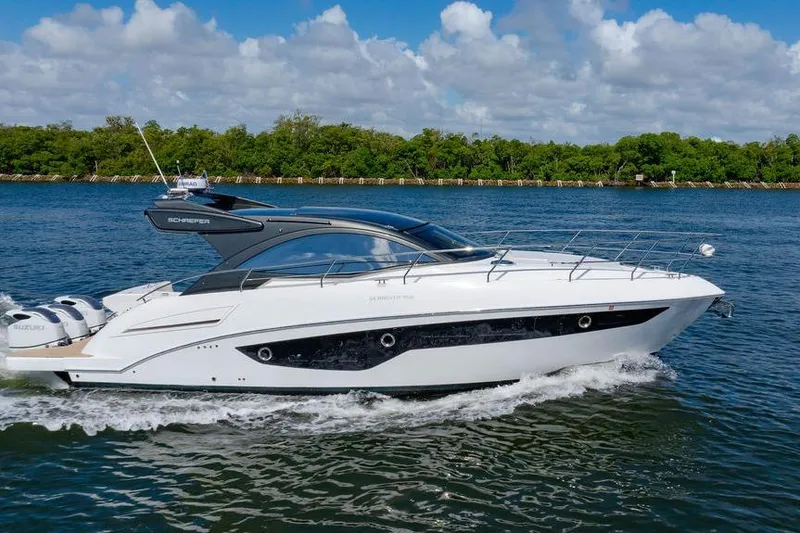 Slide: The Image of 2022 Schaefer 400 Sport yacht cruising on a sunny day, surrounded by lush greenery. - 1