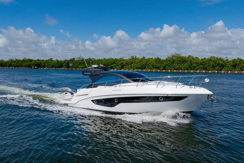 Slide: The Image of 2022 Schaefer 400 Sport yacht cruising on a sunny day, surrounded by lush greenery. - 2