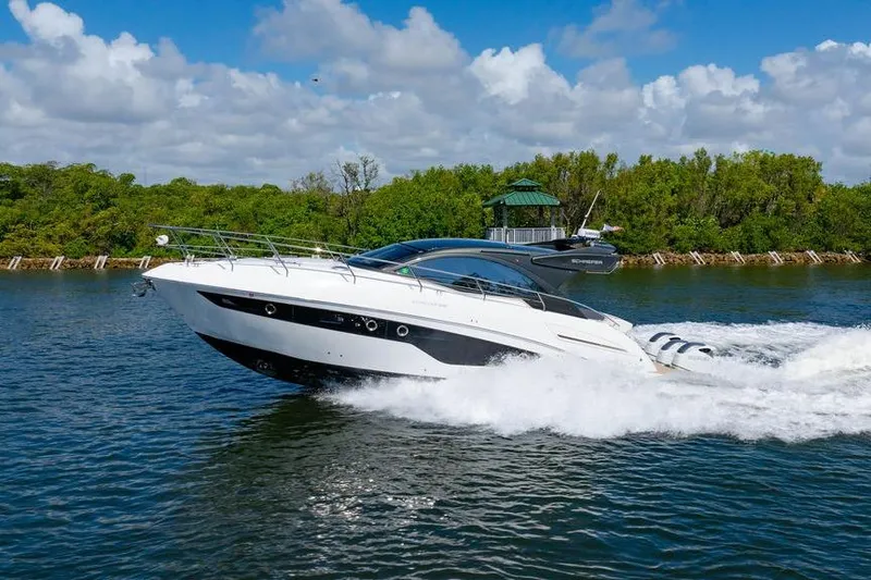 Slide: The Image of 2022 Schaefer 400 Sport yacht cruising on a scenic waterway with lush greenery. - 4