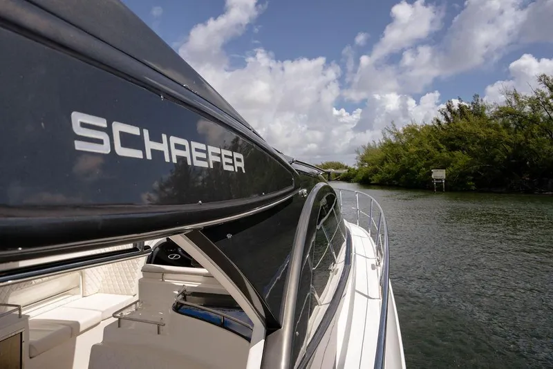 Slide: The Image of 2022 Schaefer 400 Sport yacht cruising on a scenic waterway under a partly cloudy sky. - 45