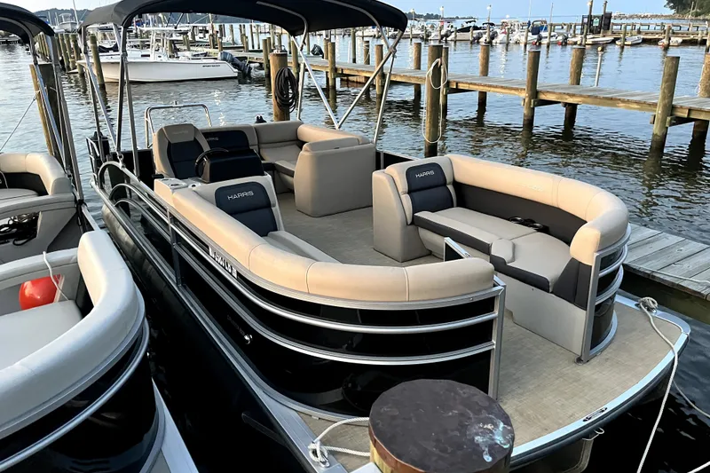Slide: The Image of 2024 Harris Cruiser 230 pontoon boat docked at marina, featuring spacious seating. - 1