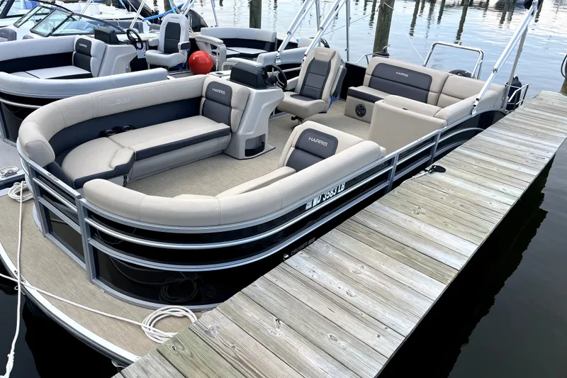 Slide: The Image of 2024 Harris Cruiser 230 pontoon boat docked, featuring spacious seating and modern design. - 2