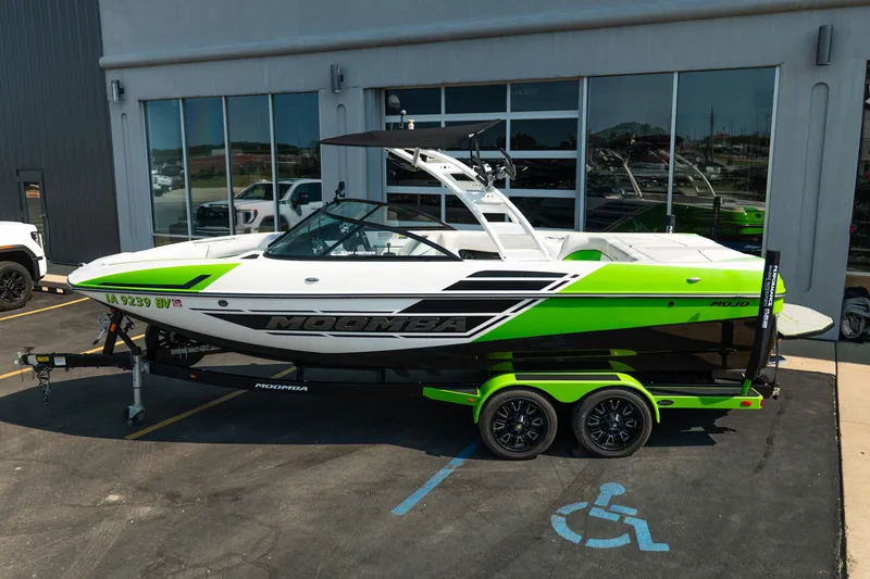 Slide: The Image of 2015 Moomba Mojo boat with vibrant green accents on a trailer, parked outside a dealership. - 5