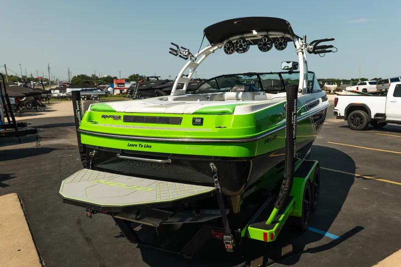 Slide: The Image of 2015 Moomba Mojo boat in vibrant green, parked on a trailer in a lot. - 7