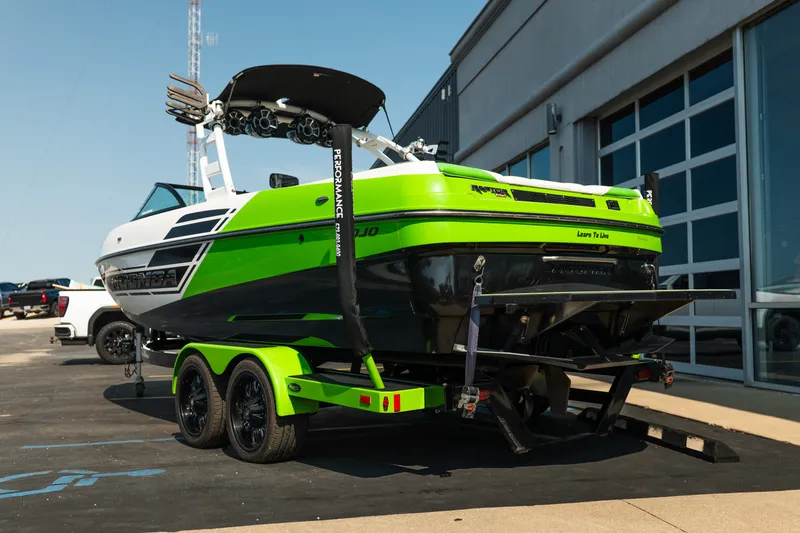 Slide: The Image of 2015 Moomba Mojo boat on trailer, vibrant green and black design, parked near a building. - 6