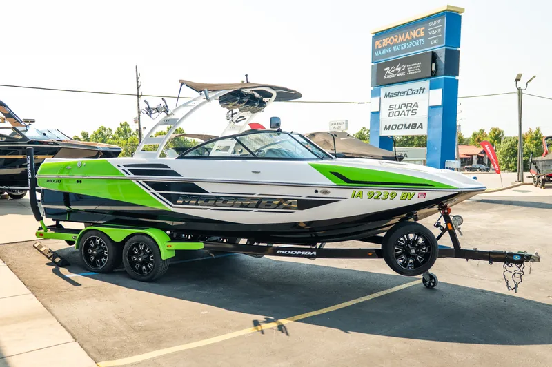 Slide: The Image of 2015 Moomba Mojo boat with vibrant green accents on a trailer at a dealership. - 10