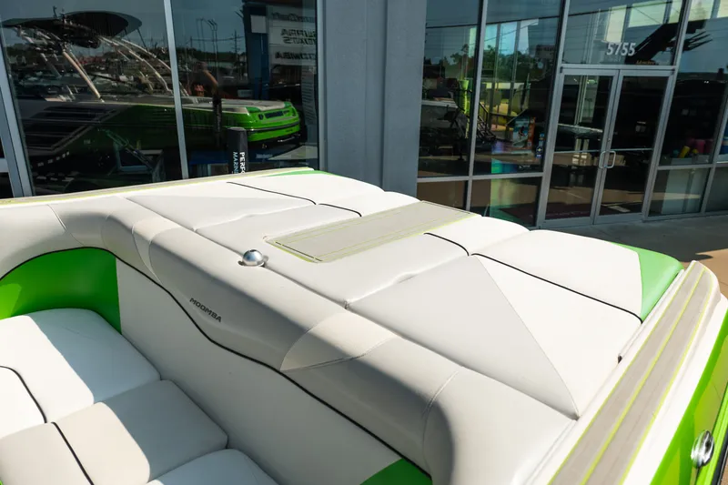 Slide: The Image of 2015 Moomba Mojo boat with green and white upholstery, parked outside a showroom. - 17
