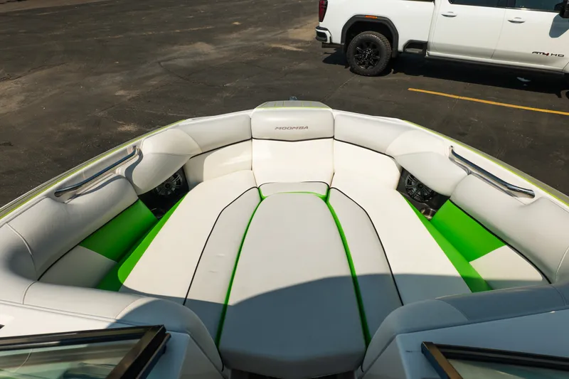 Slide: The Image of 2015 Moomba Mojo boat interior with white and green seating, parked near a white truck. - 33