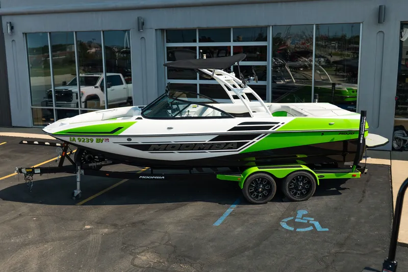 Slide: The Image of 2015 Moomba Mojo boat with vibrant green accents on a trailer outside a dealership. - 4