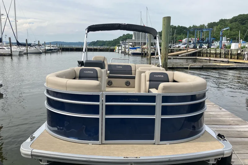 Slide: The Image of 2024 Harris Cruiser 230 pontoon boat docked at a marina. - 2