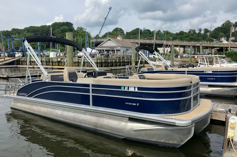 The Image of 2024 Harris Cruiser 230 pontoon boat docked at a marina under cloudy skies. - 0