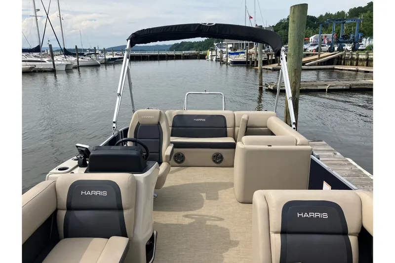 Slide: The Image of 2024 Harris Cruiser 230 pontoon boat docked at a marina, featuring spacious seating. - 4