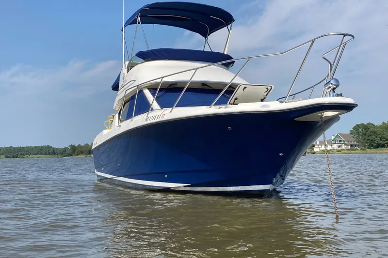 Slide: The Image of 2007 Bayliner Discovery 288 boat anchored on calm water under a clear sky. - 2