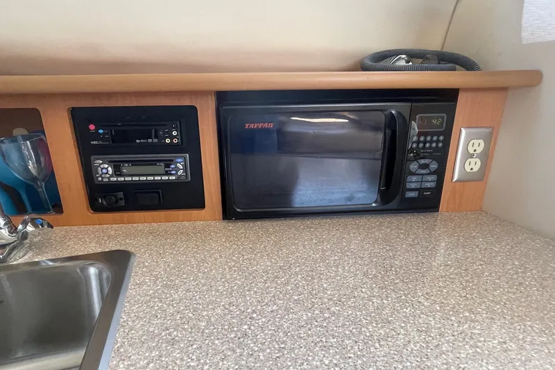 Slide: The Image of 2007 Bayliner Discovery 288 galley with microwave, stereo system, and countertop. - 16