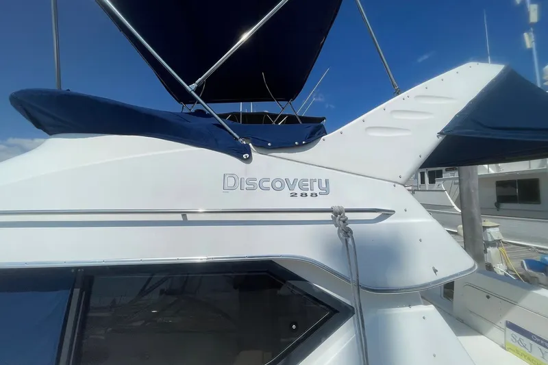 Slide: The Image of 2007 Bayliner Discovery 288 boat with blue canopy, docked under clear sky. - 31